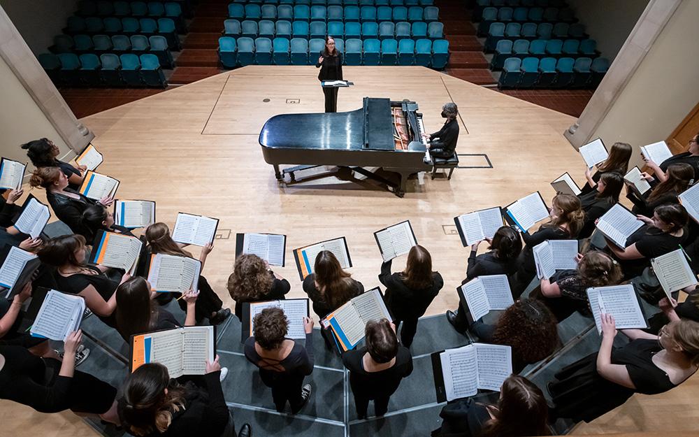Overhead view looking down at the choir on risers in an arc, holding music open.