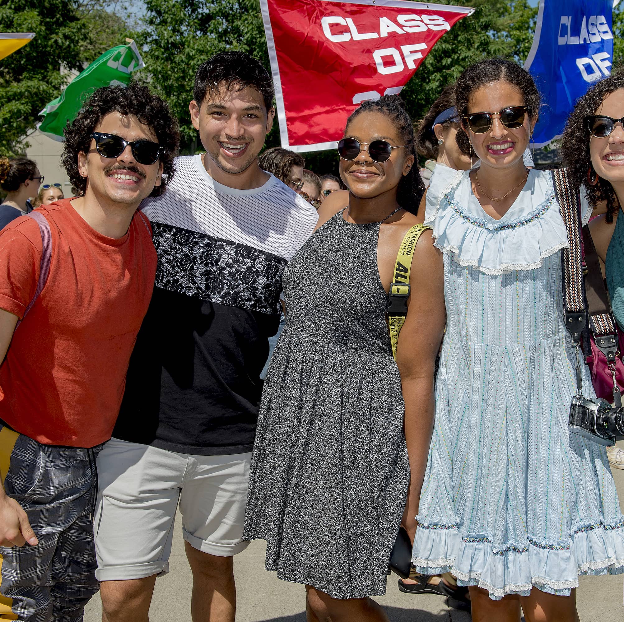 A group of people standing arm in arm at an event smile at the viewer.