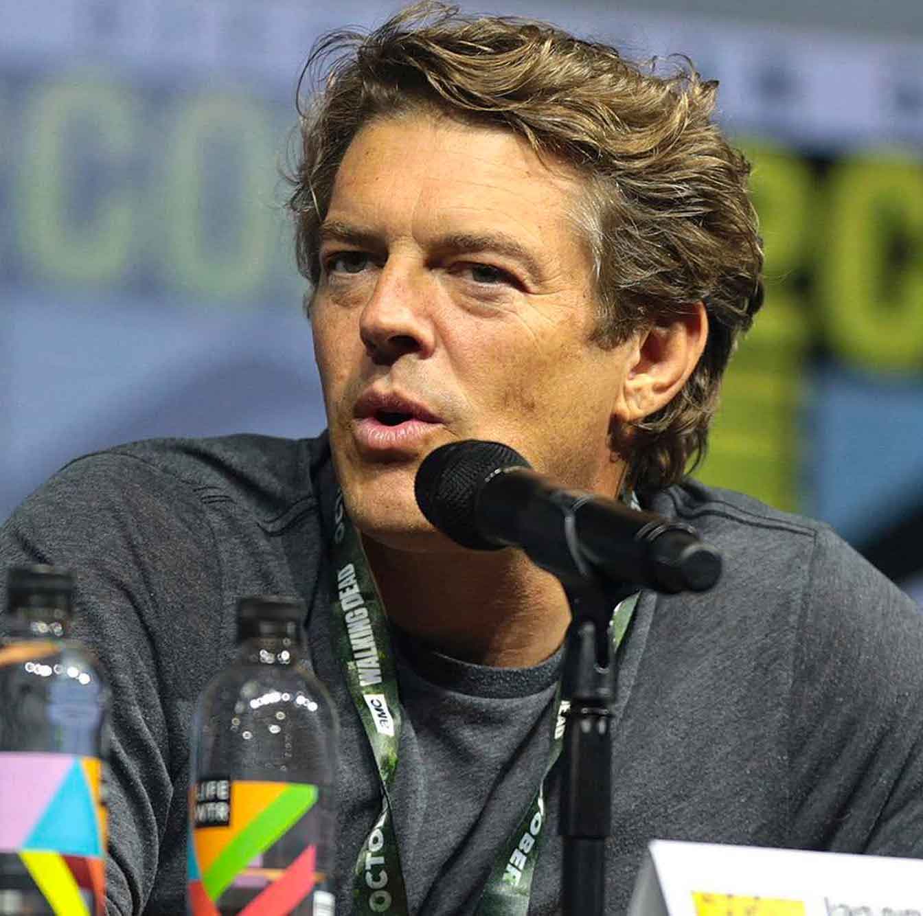 Vassar alum Jason Blum, a person with short thick brown hair and a grey shirt, speaking into a microphone looking off to one side of the viewer.
