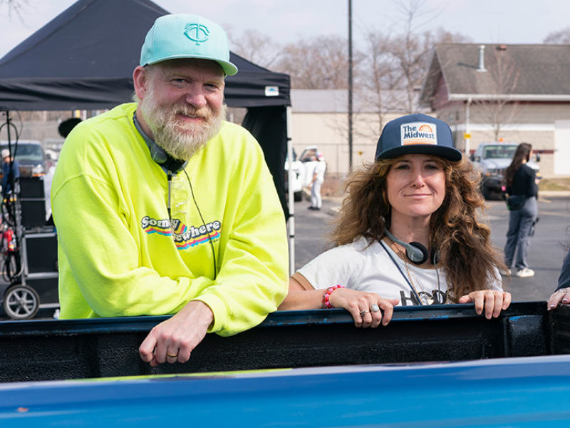 A photo of Paul Thureen ’00 and Hannah Bos ’00. Paul is tall, with a gray beard and a green baseball cap. Hannah is shorter, with long brown hair and a blue baseball cap.