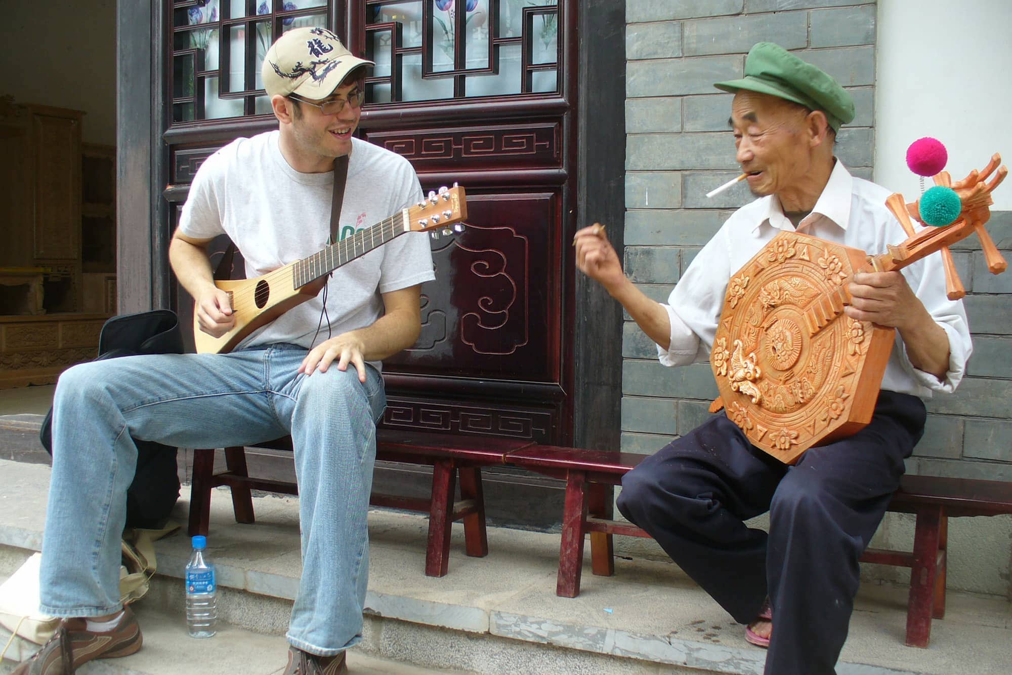 Two people of different ages sit holding unusual stringed instruments looking at each other.
