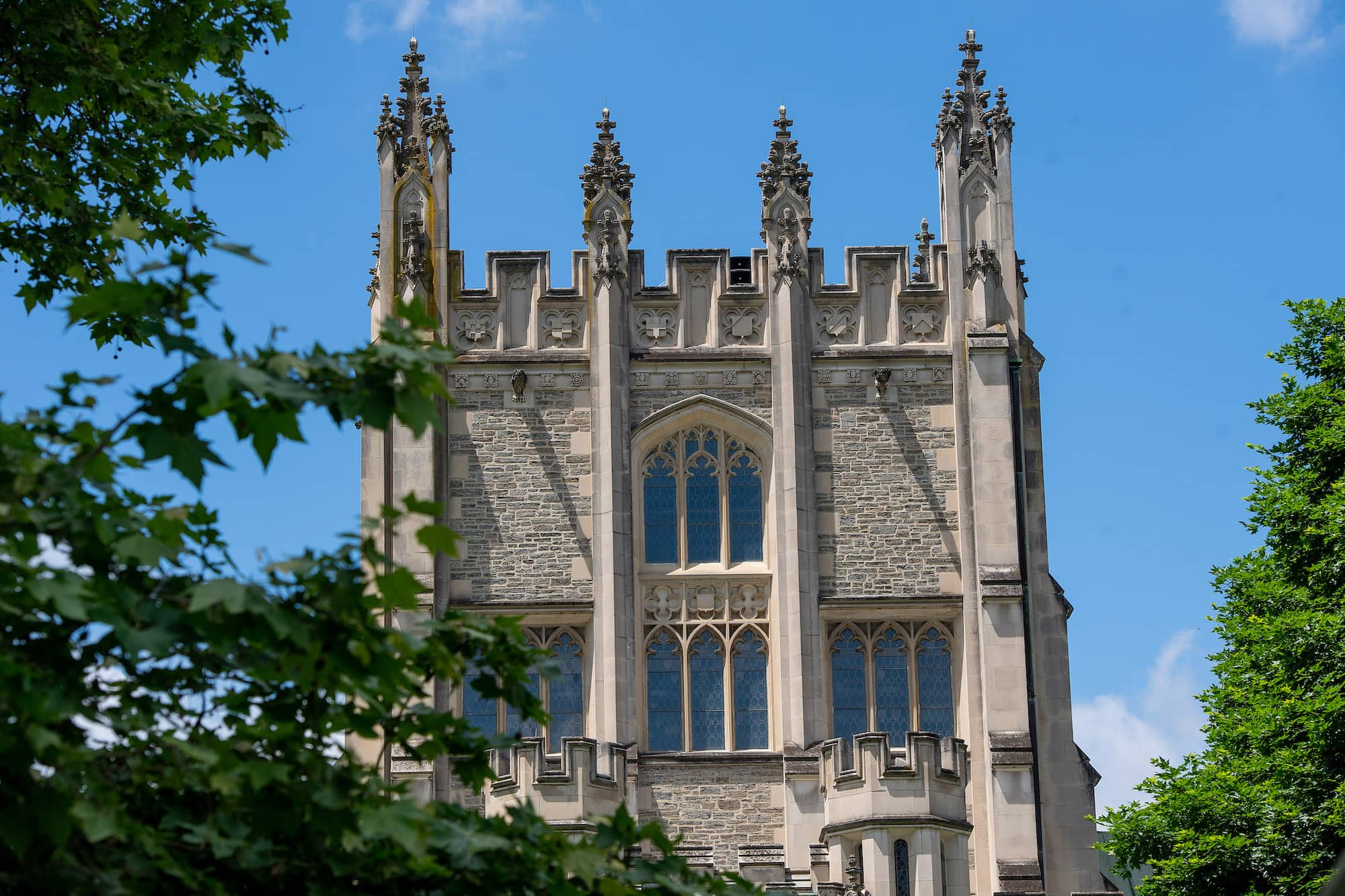 A detailed view of the top of the central tower of Thompson Library on Vassar Campus, a large, stone building with stained-glass windows and classical architecture.