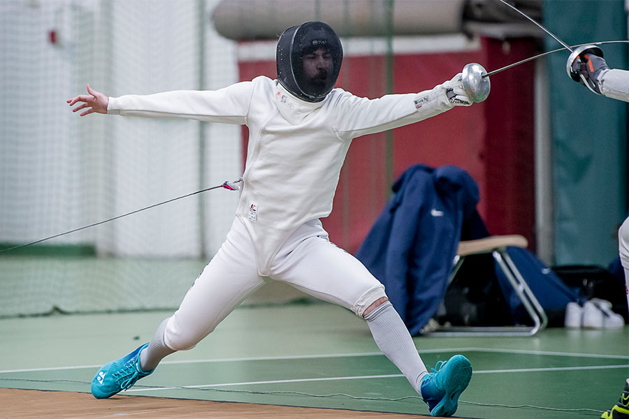 During a match, Eli Weise ’25 with sword outstretched lunges toward his opponent.