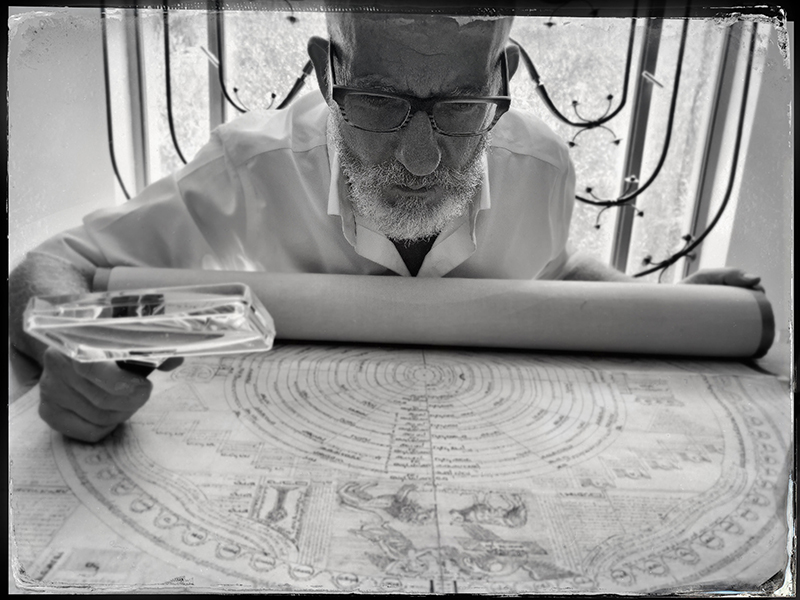 Professor J. H. (Yossi) Chajes poring over a manuscript with a magnifying glass.