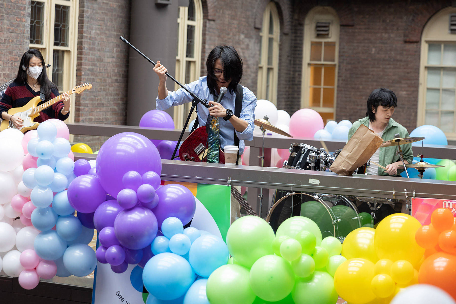 Musicians on a stage with rainbow colored balloons in front of them