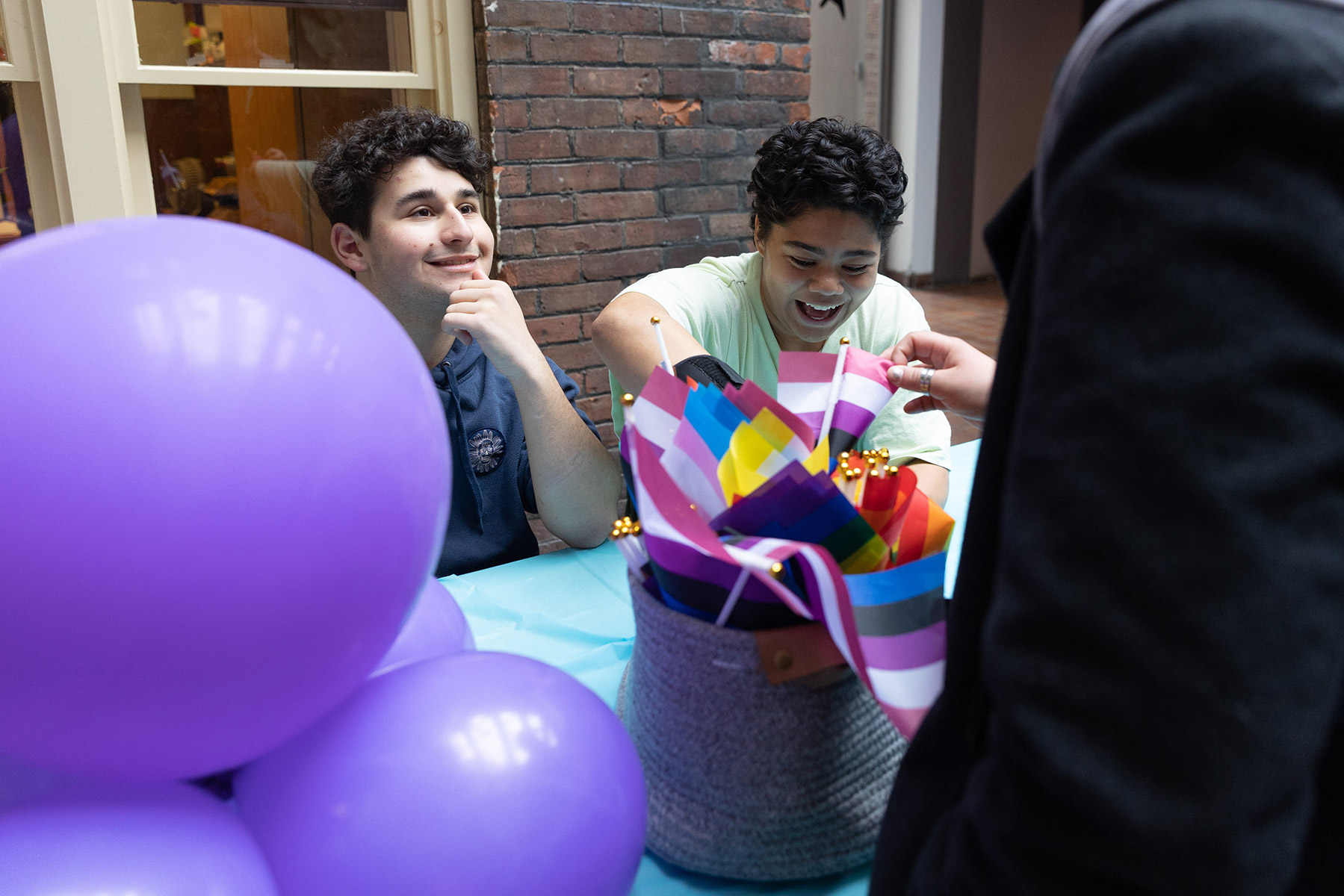 Two people sitting at a desk with with purple balloons in front of them