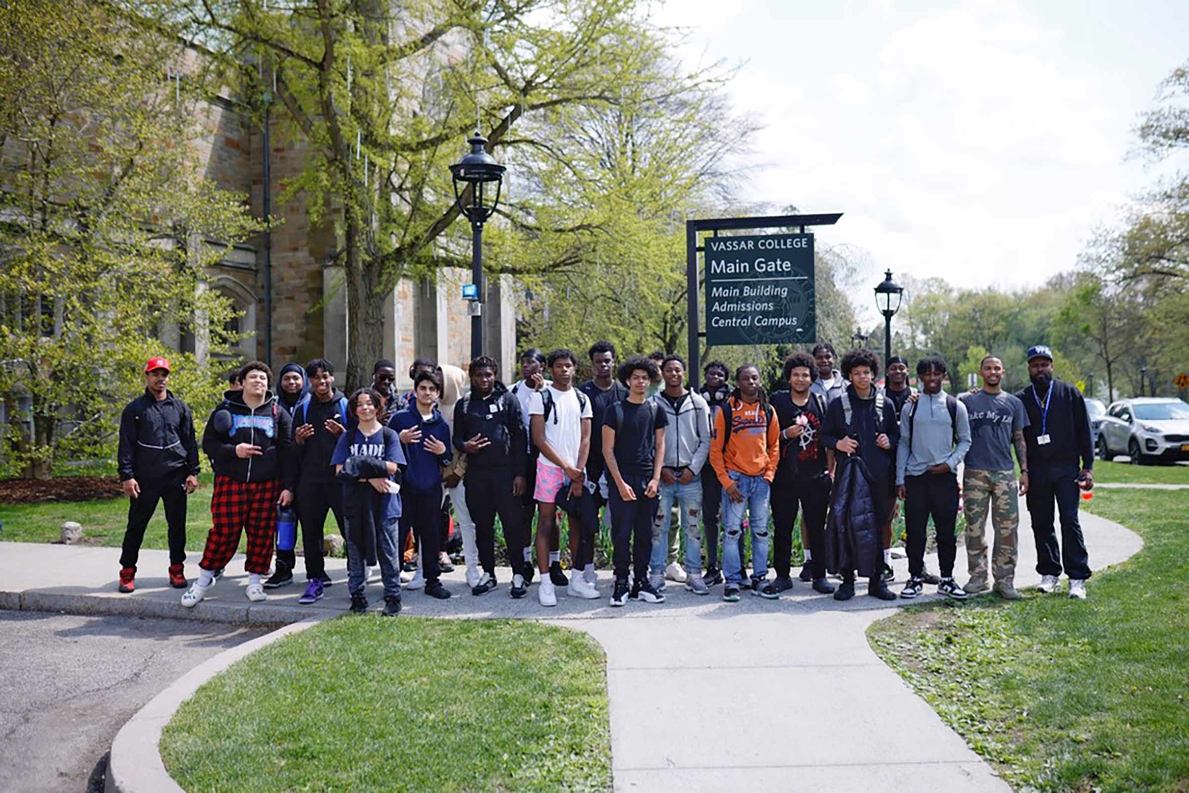 Devyn Benson stands in front of Vassar sign with students from Kingston High School and Franklin D. Roosevelt High School.
