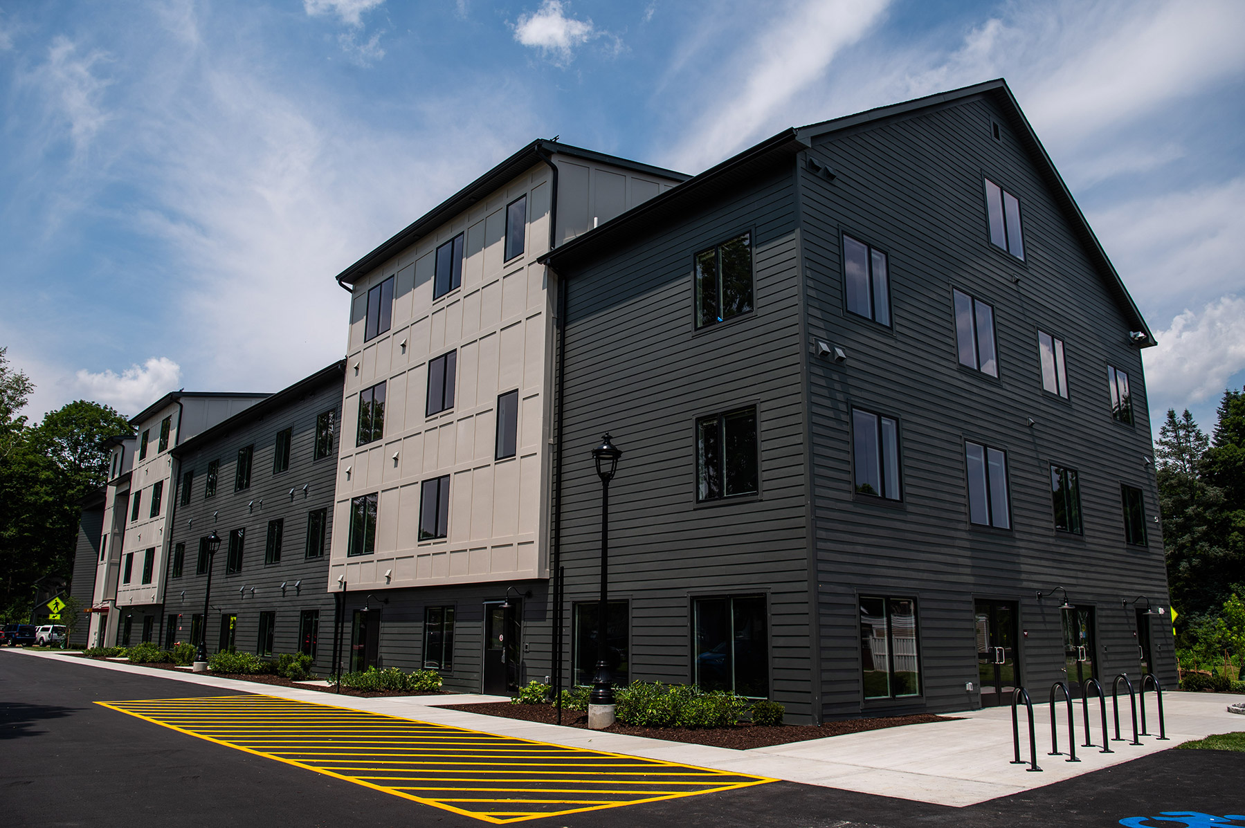 Exterior of a large, modern, grey building with walkway and street around it.