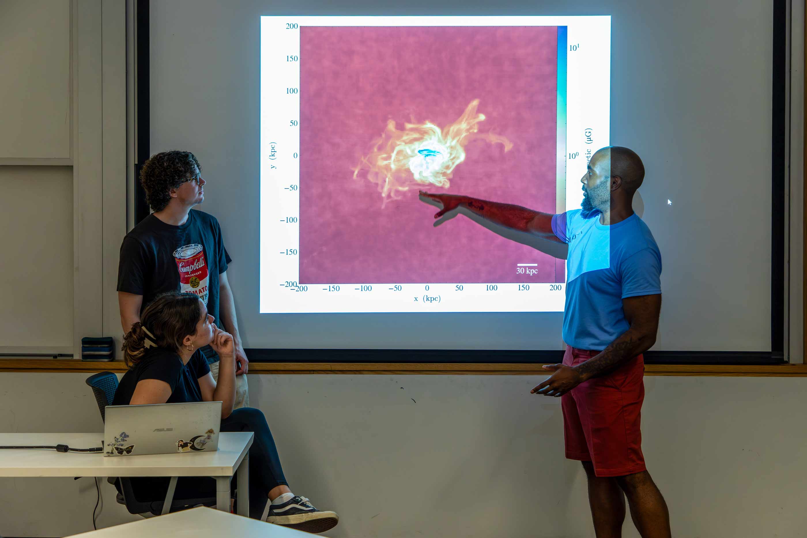 Assistant Professor of Astronomy Ed Buie II pointing to projection of circumgalactic medium.