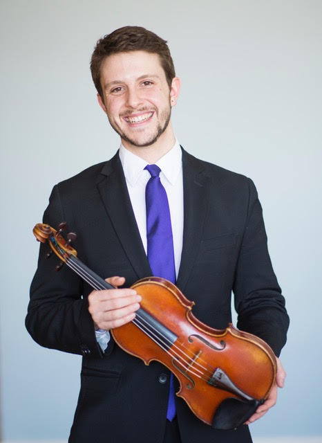 Person smiling in a suit and blue tie holding a violin