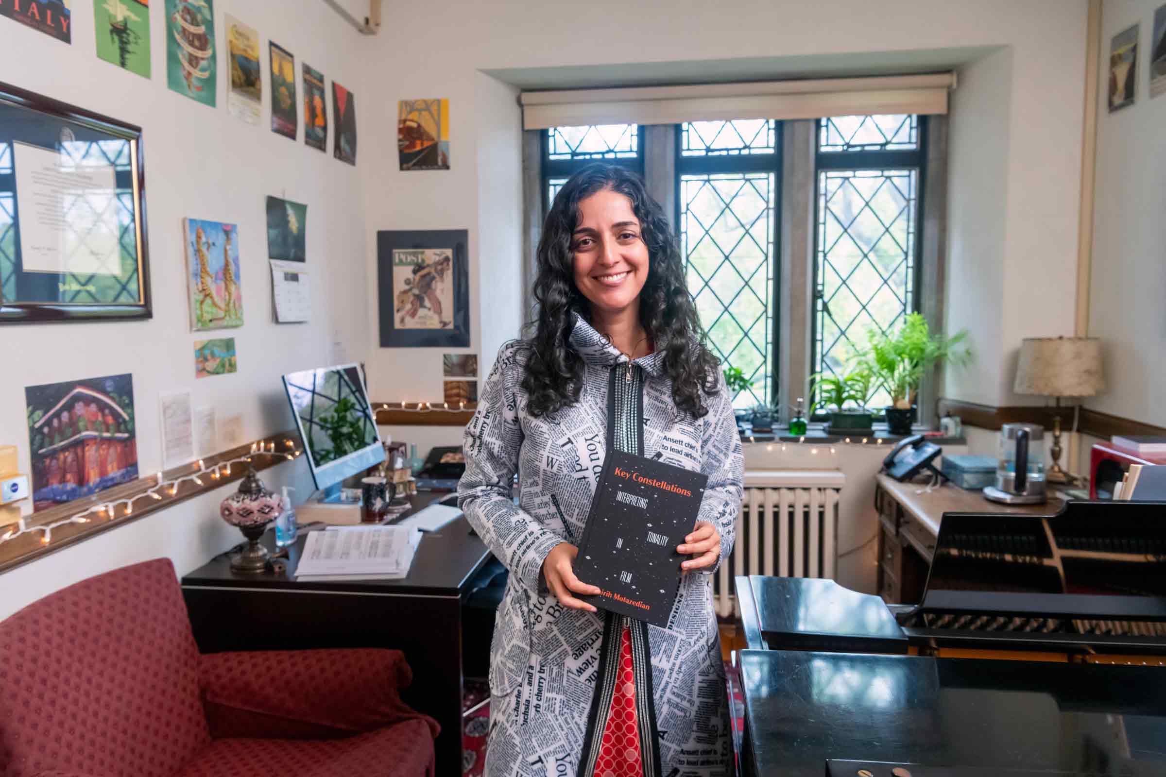 Smiling person holding a book in a study