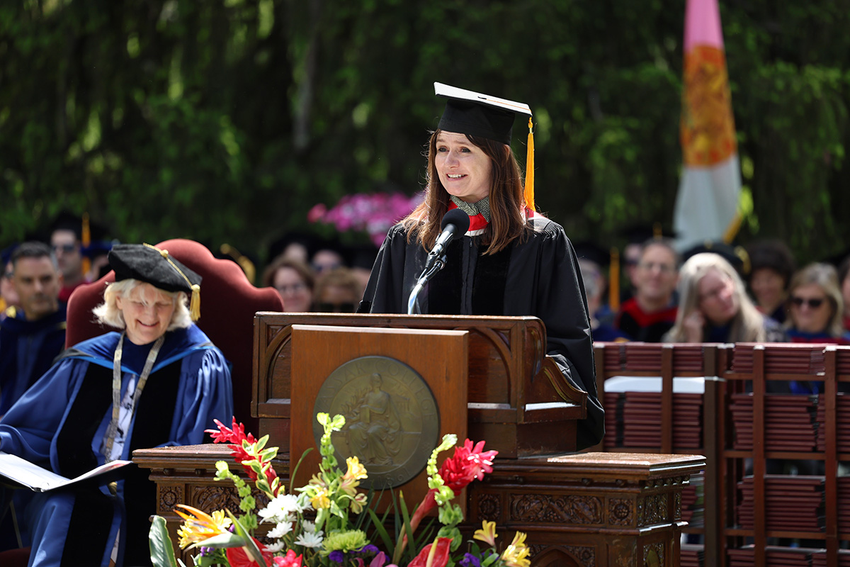 The commencement speaker in academic attire at the podium during a graduation ceremony.