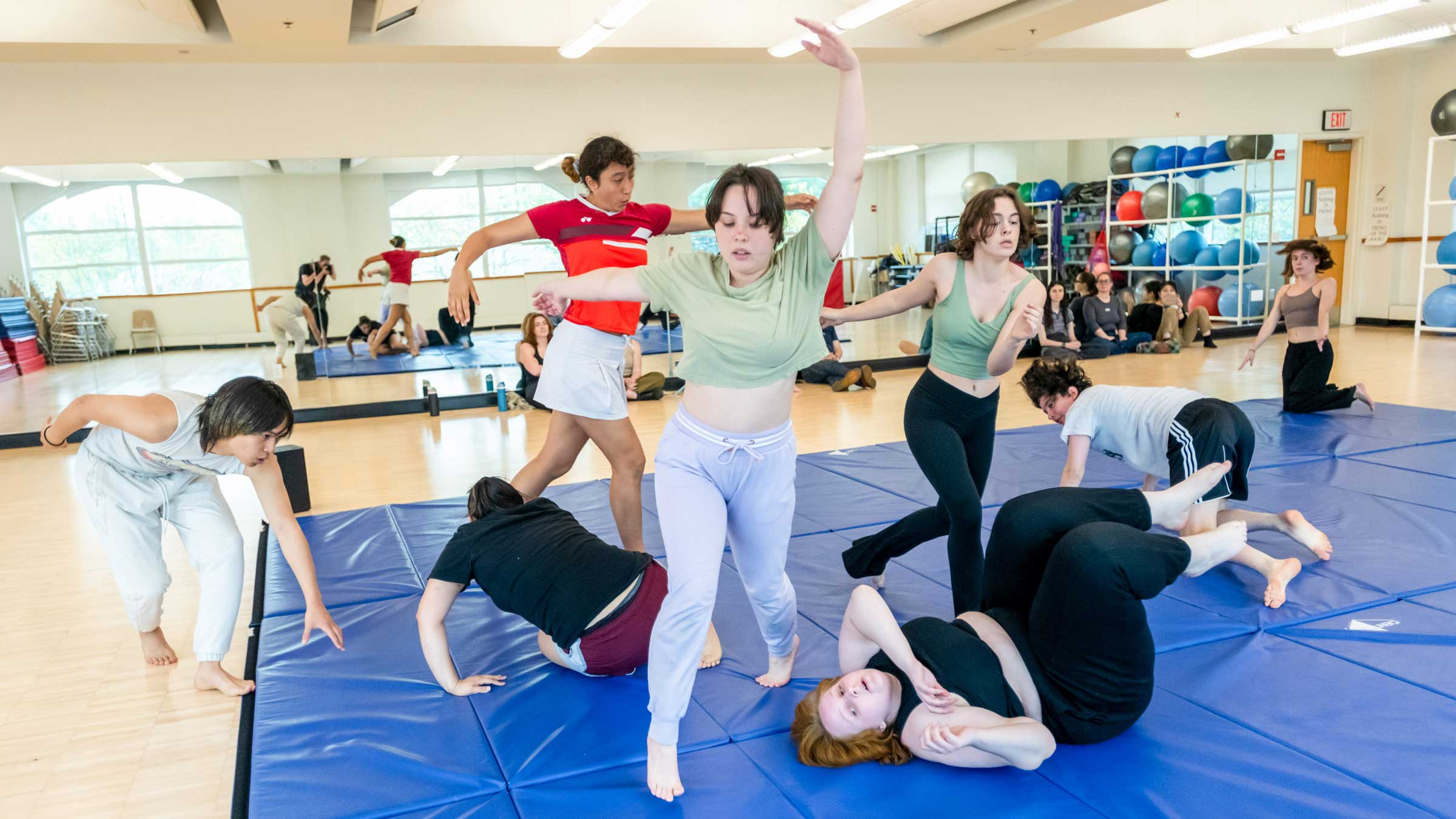 Group of people on a mat practicing dramatic acrobatics.