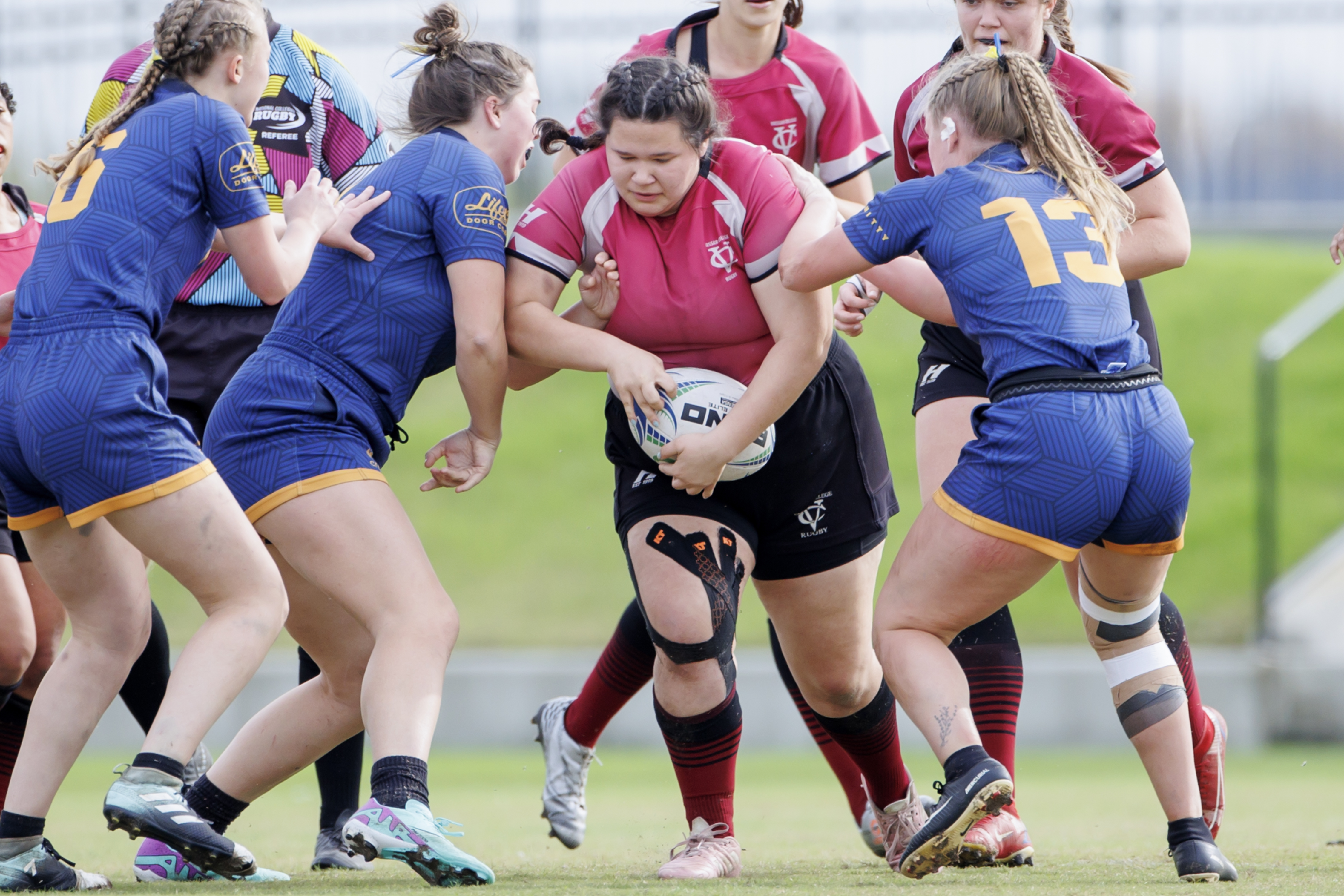 Andie Authers, holding the ball, pushes through a group of opponents during a rugby game.