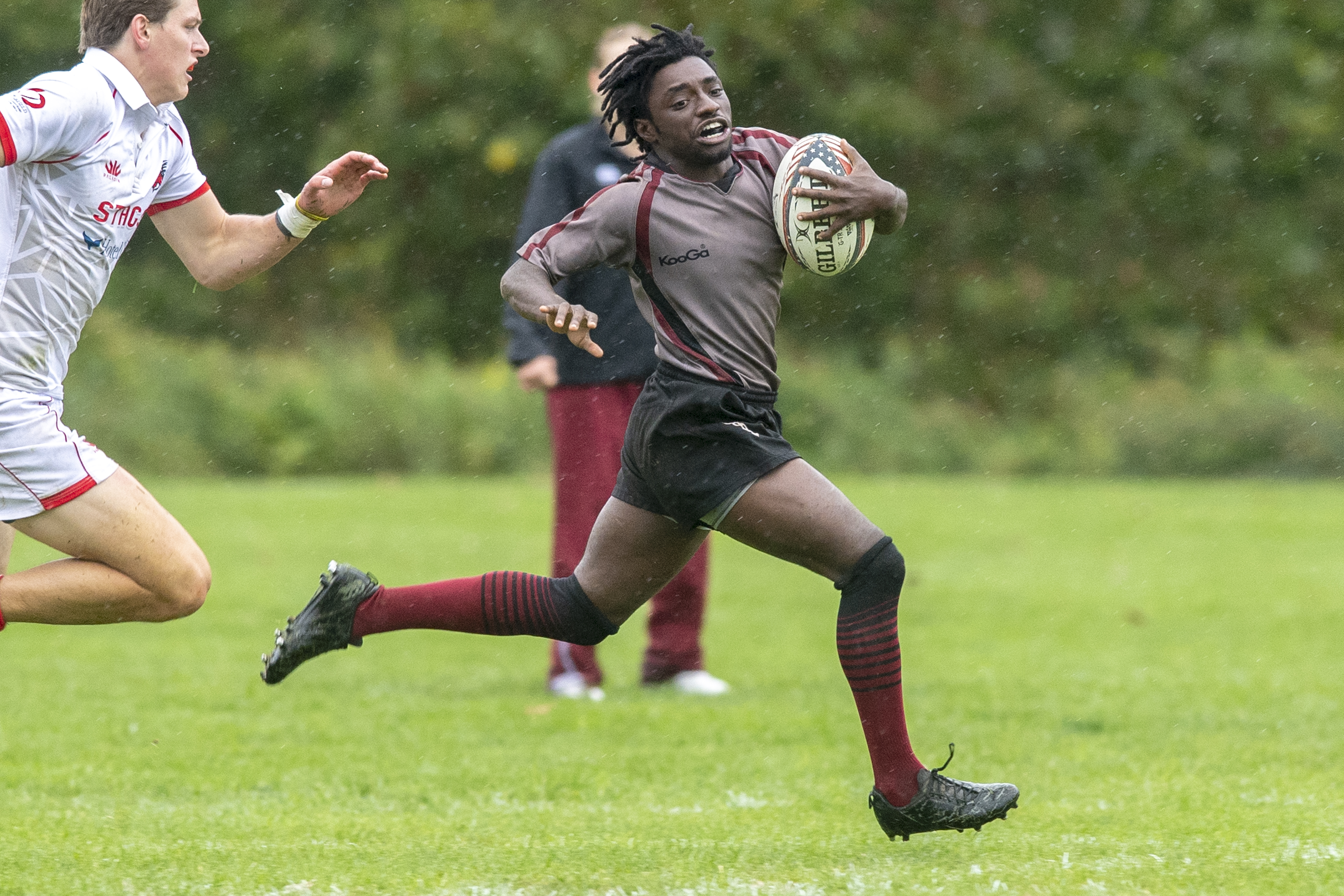 TJ Usher runs with the ball as an opponent chases him during a rugby game.