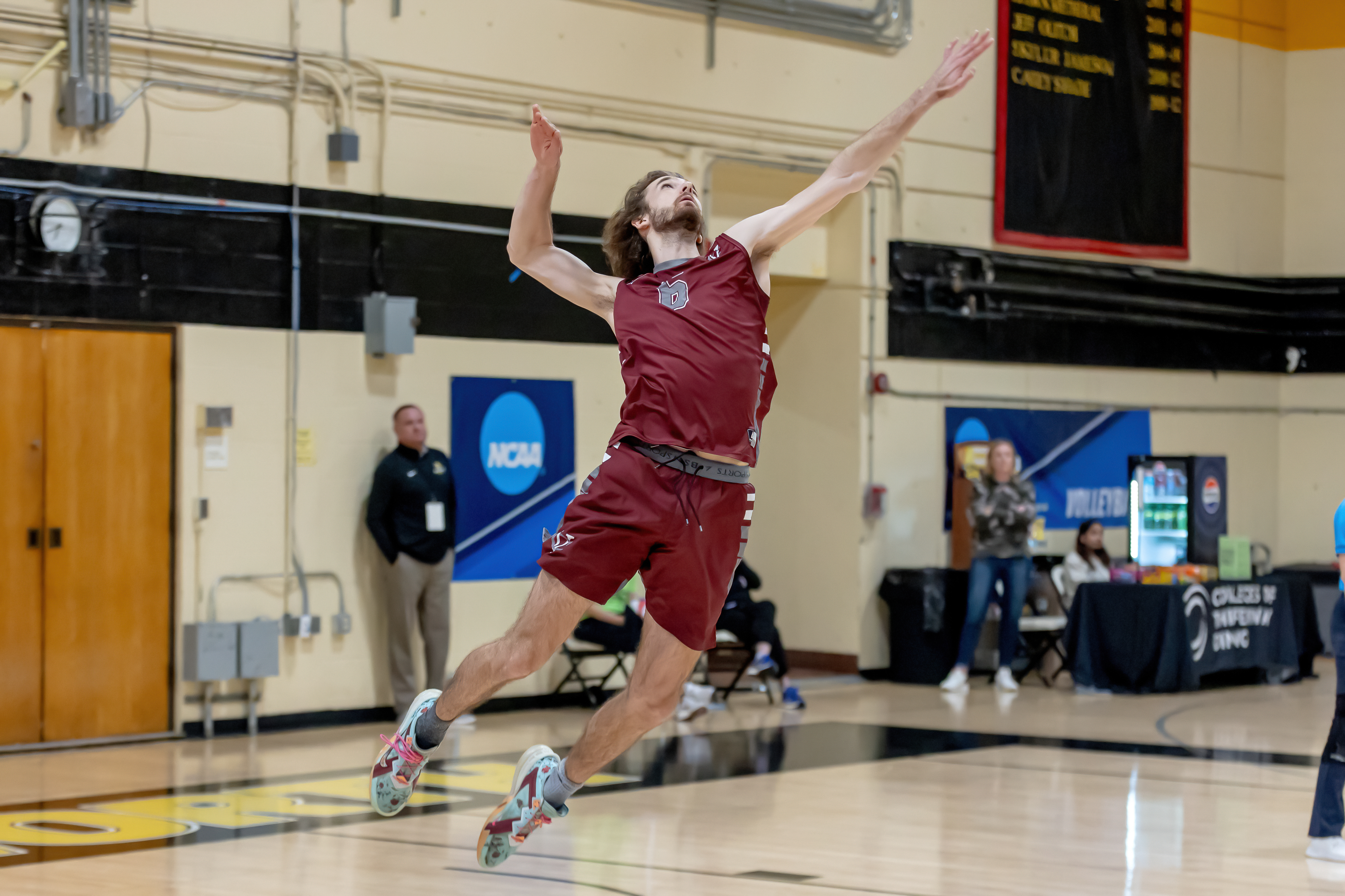 Vaughn Ramsey jumps up to hit the ball during a volleyball game in a gym.