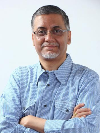 A headshot of Dr. Anurag Mehra, a person with short gray hair, a short gray beard, and glasses.