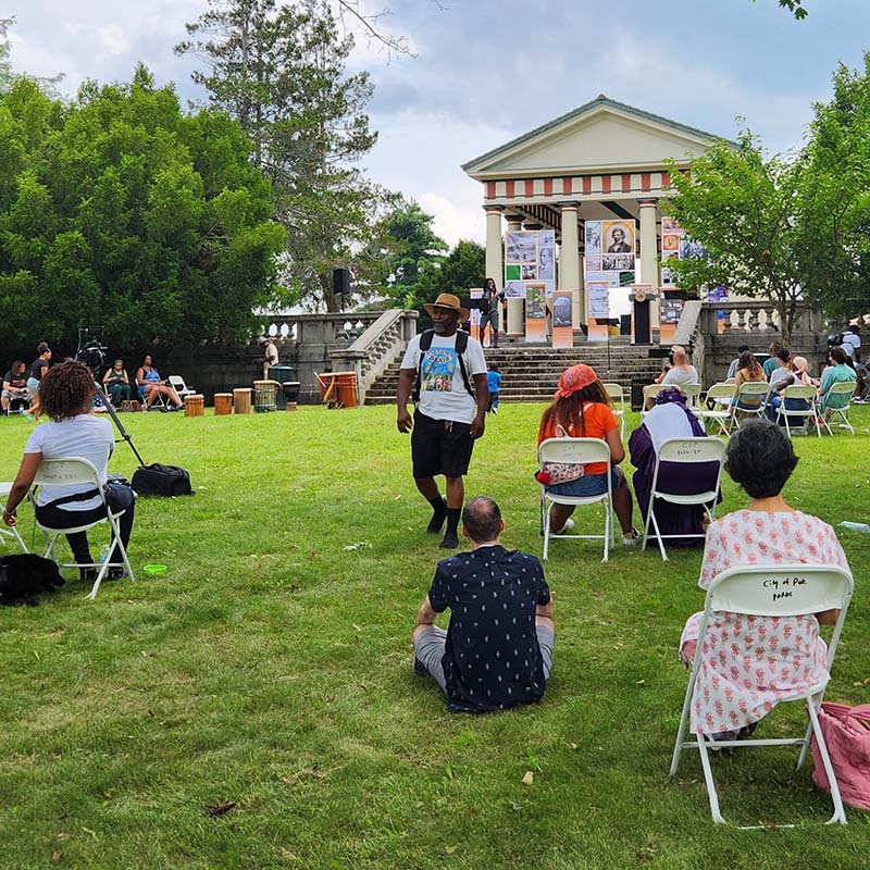 A smattering of people on a lawn attend an event on a sunny day.