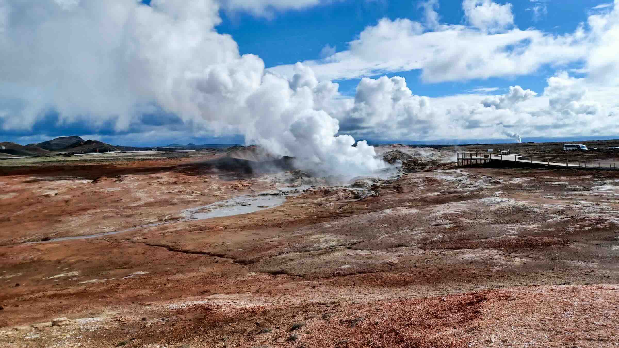 A Geothermal area in a barren landscape spewing steam from the ground.
