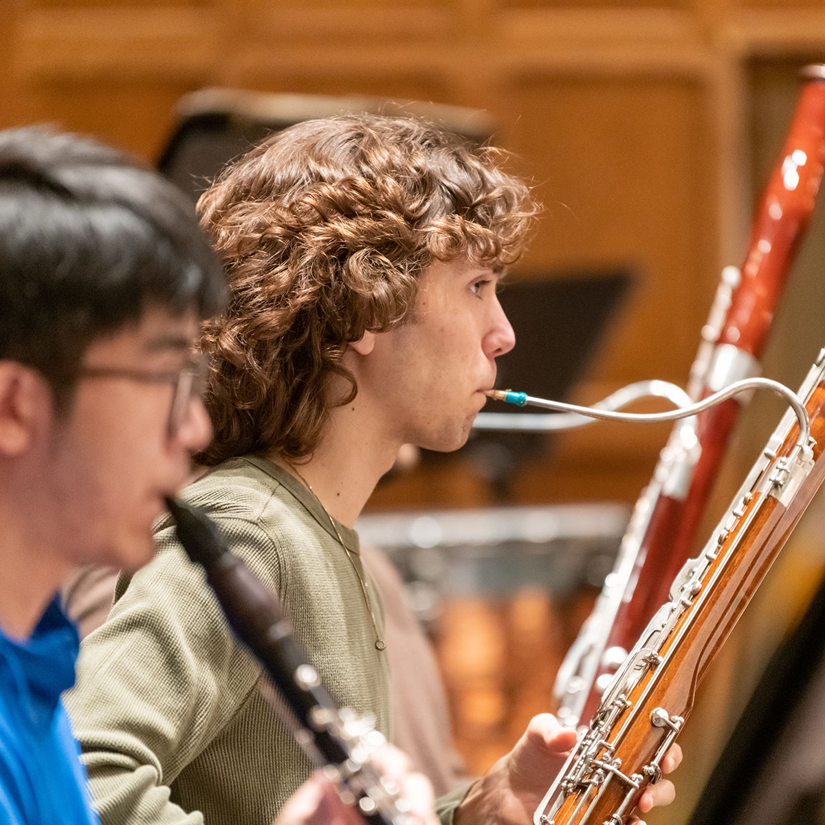 Two people blowing into a wind instrument on stage during a concert.