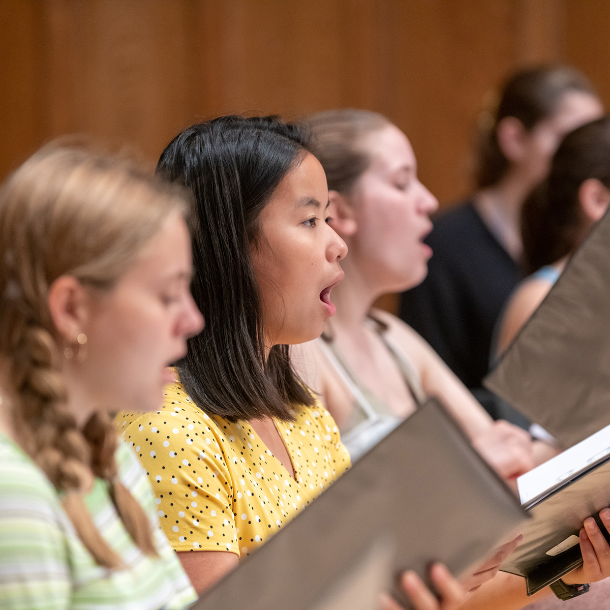 People on a stage holding open books and singing.