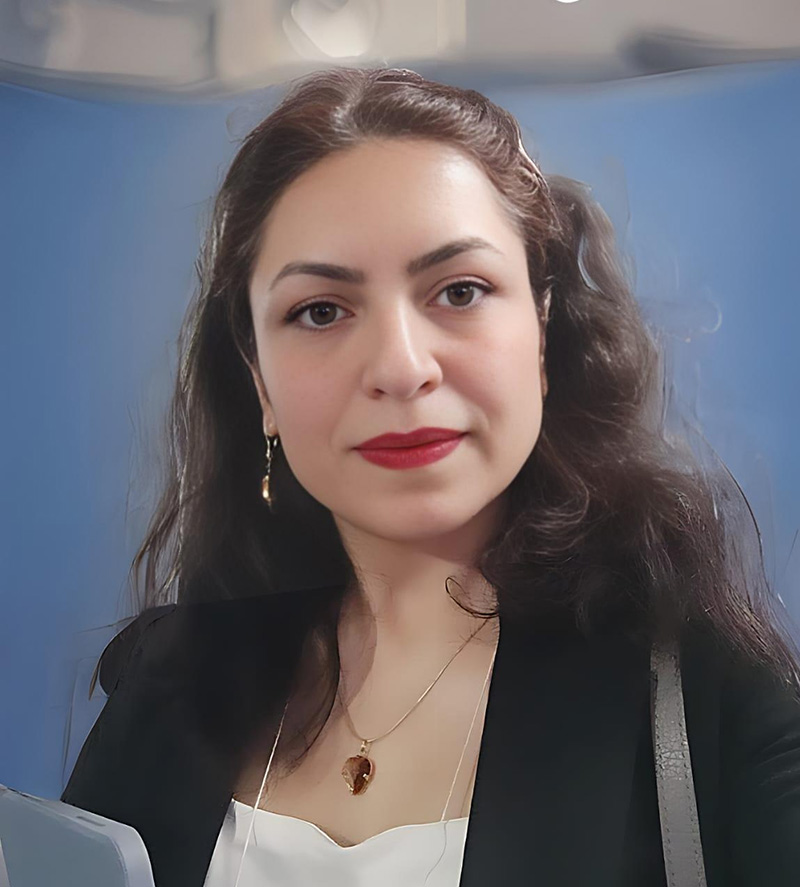 Portrait of a person with long brown curly hair in a nice suite jacket and white shirt.