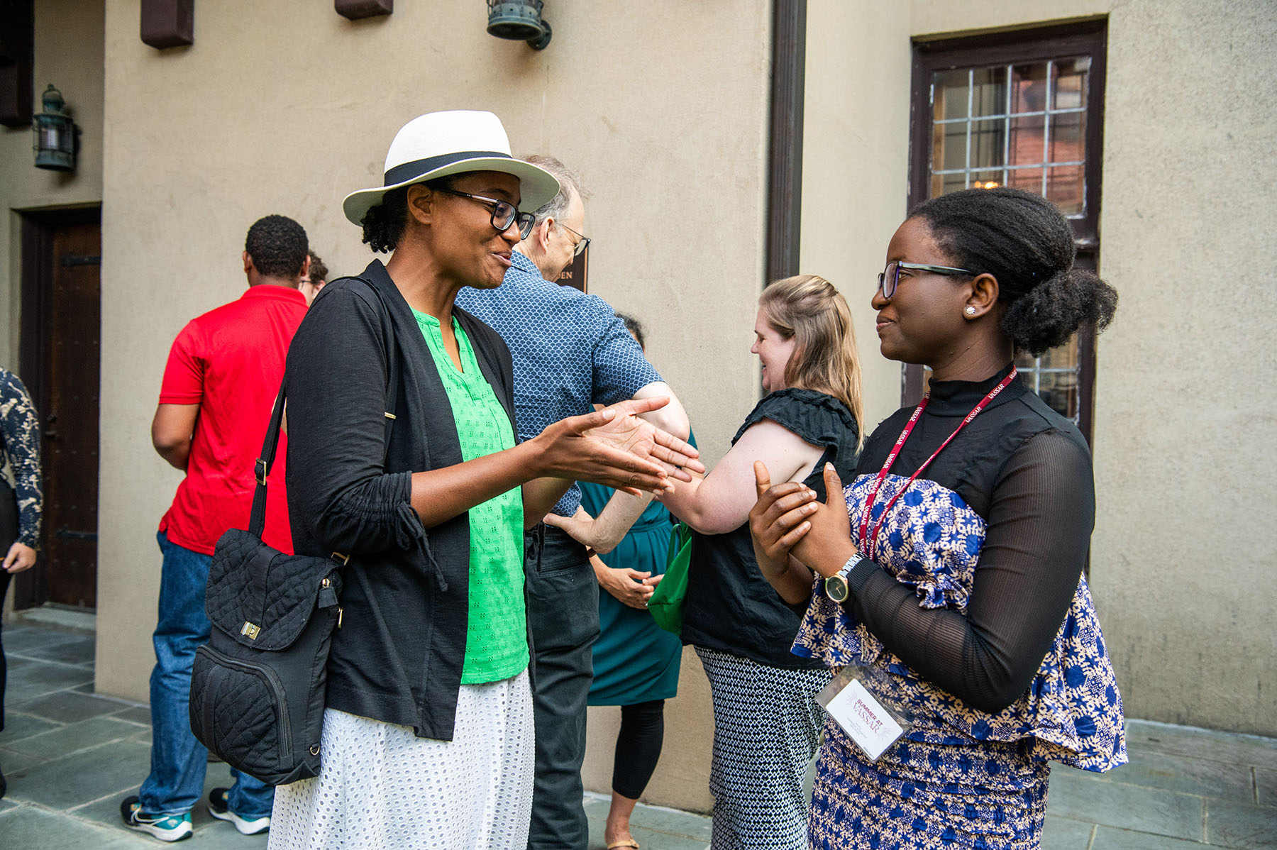 Two people standing outside of a building looking and talking to each other.