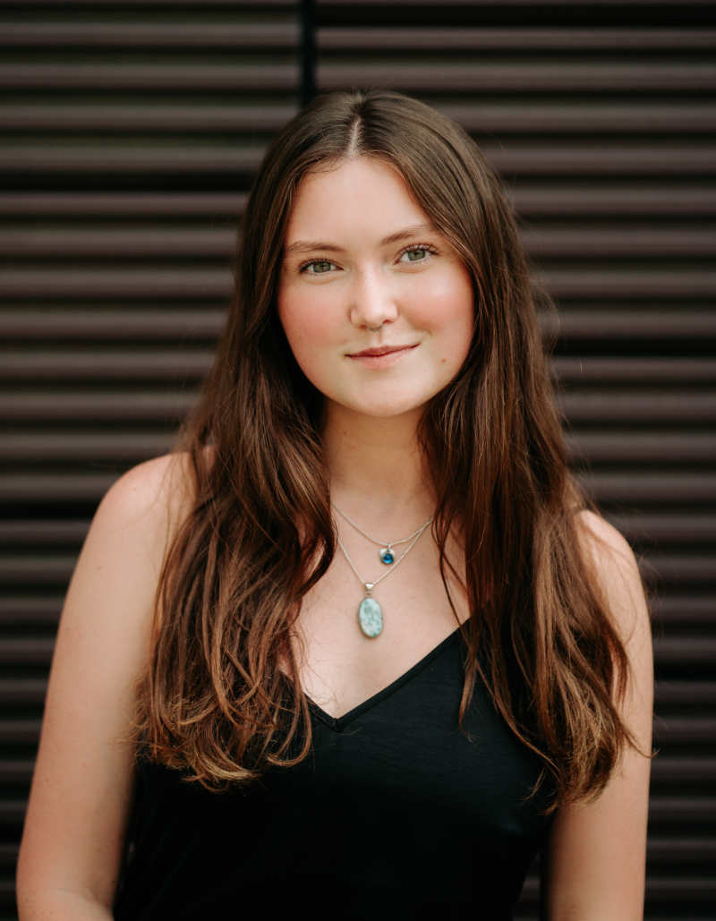 A portrait of Anna O’Shea, a person with long brown hair and a black dress.