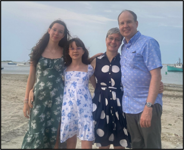 Four people standing side-by-side posing for a photo on a beach.