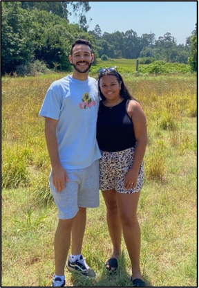 Two people standing side-by-side outside in a field.