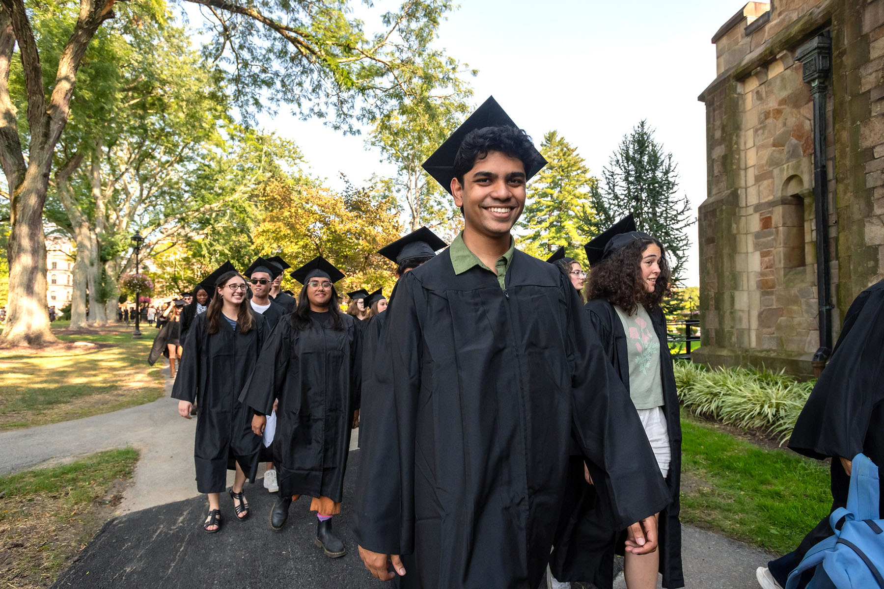 Students in grduation caps and gowns lined up outside preparing to parade into convocation.