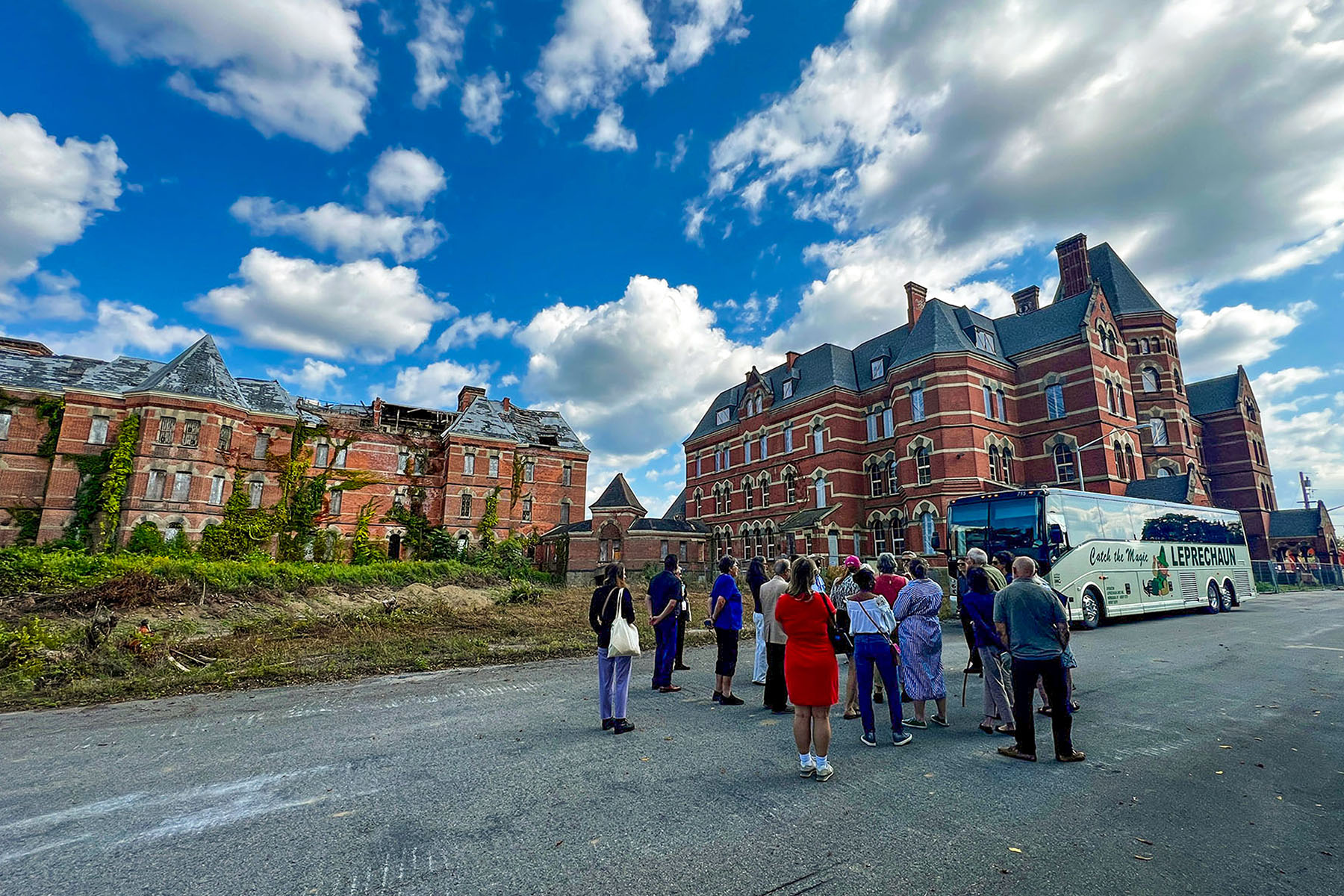 Group of people standing on a street in front of a red-brick building.