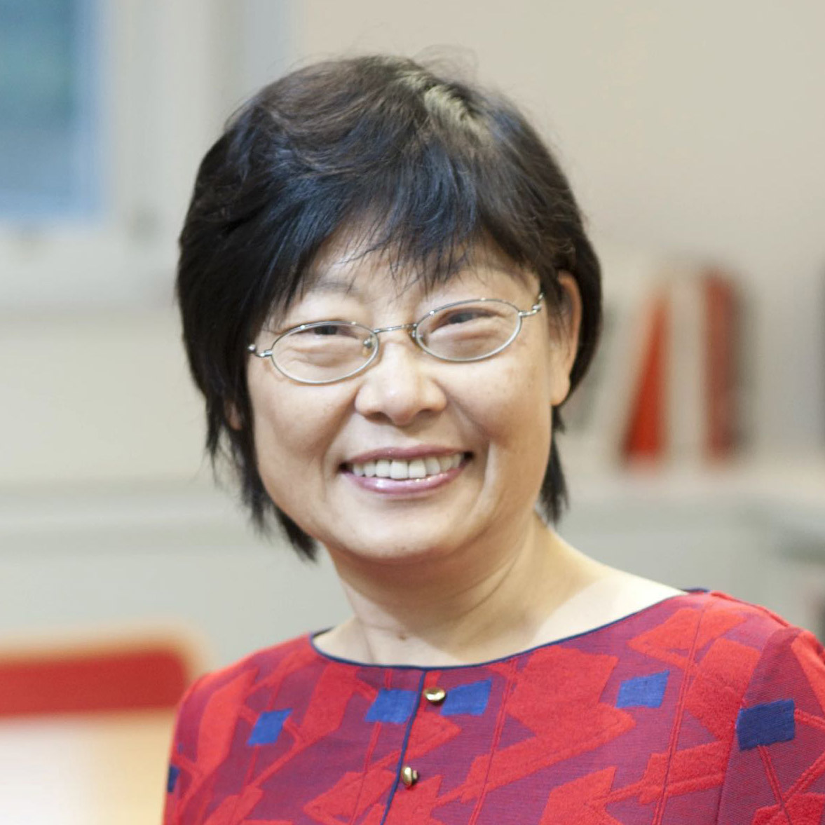 Portrait/headshot of a person with glasses, black hair and a red shirt.