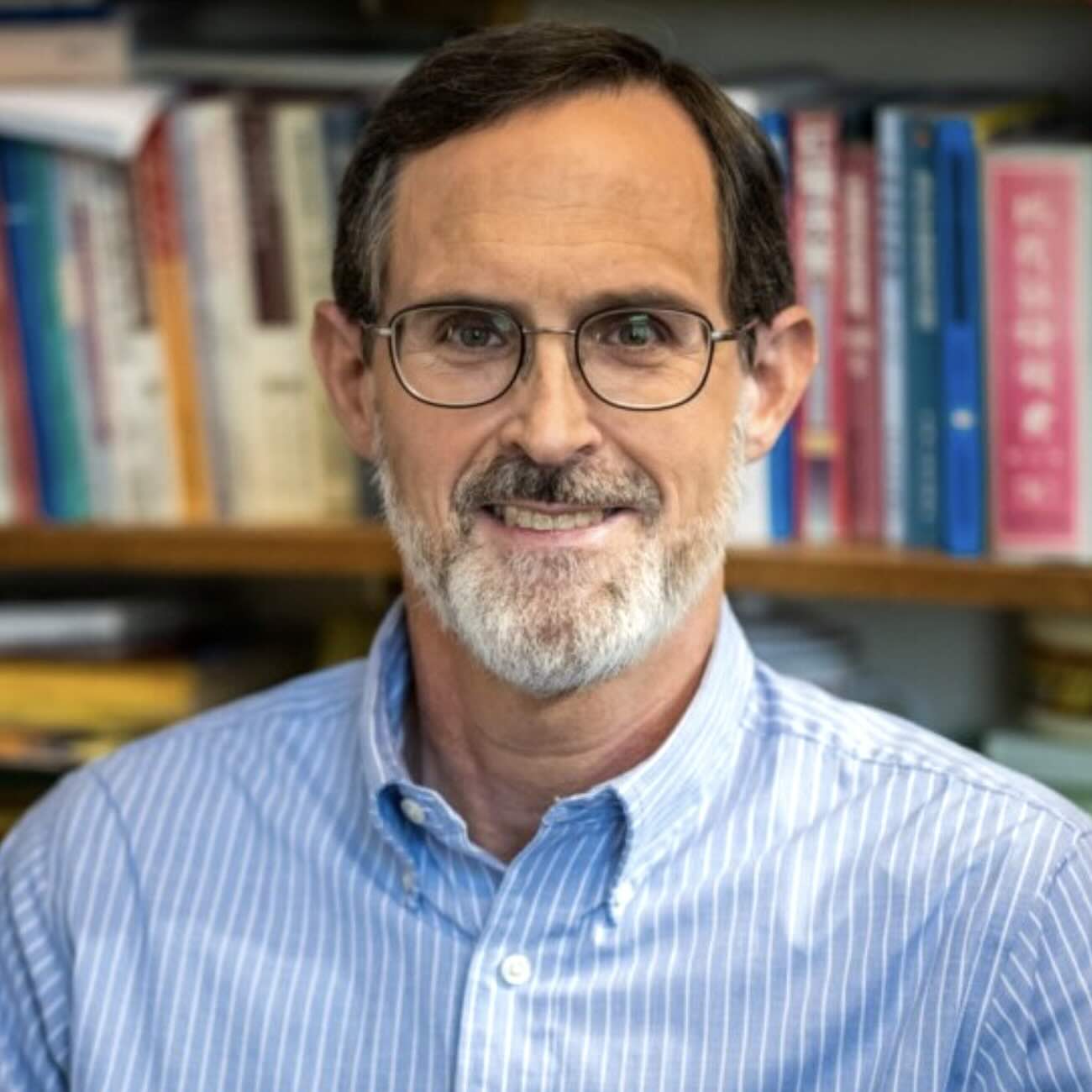 A headshot of Kenneth Foster, a person with brown hair, glasses, and a gray beard.