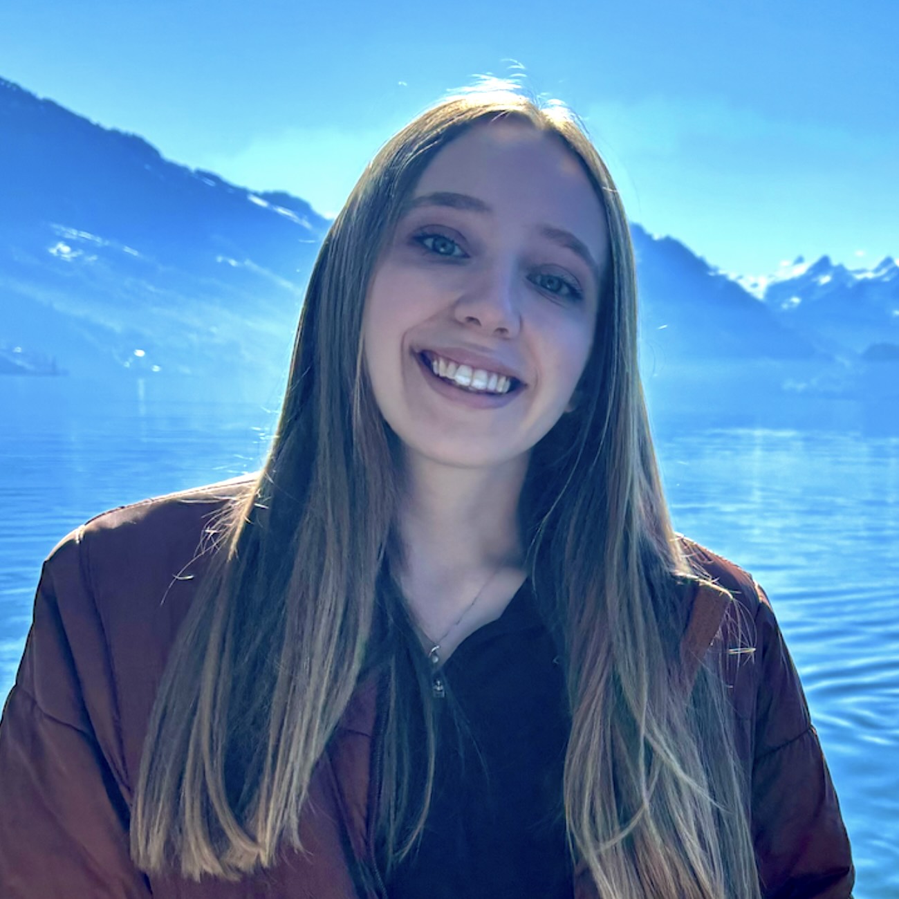 A headshot of Madi Sandy, a person with long blond hair and a burgundy jacket.