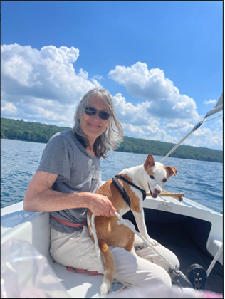 Person sitting on a small boat with a dog in their lap.