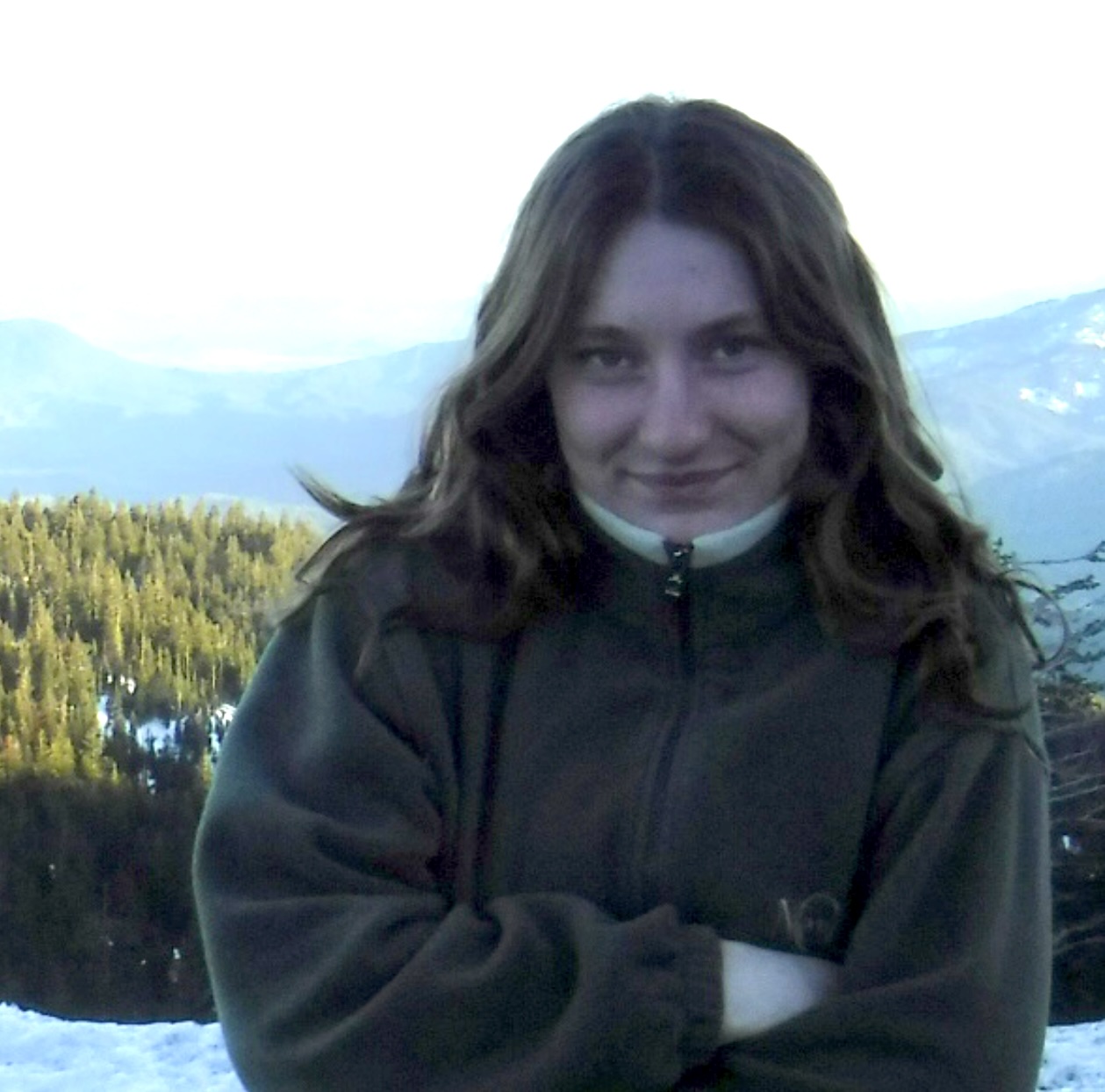 A headshot of Mira Saturen, a person with long brown hair and a dark-colored sweater.