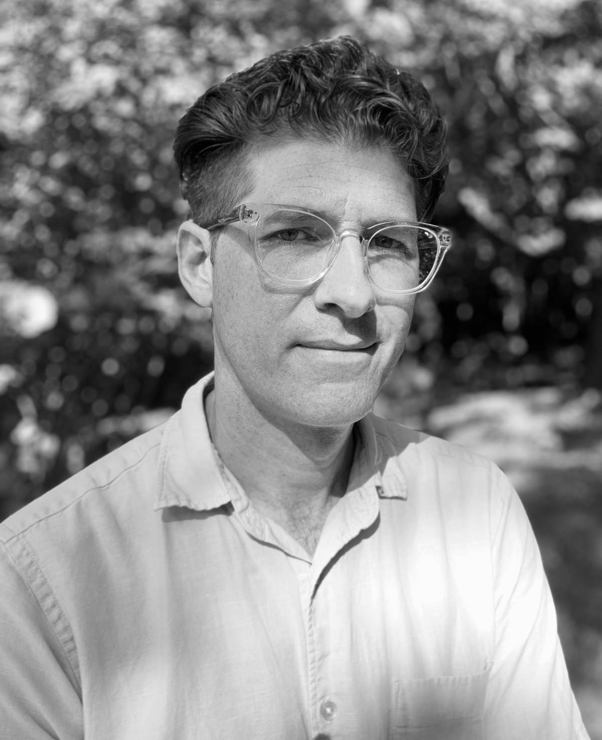 A black and white photo of Richard Ocejo, a person with short dark hair and glasses.