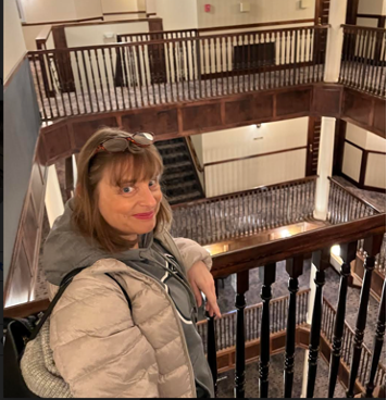 Person standing upstairs leaning against a railing.