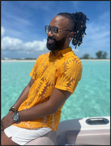 Person sitting with a yellow shirt and dark hair with crystal blue/green island waters in the background.