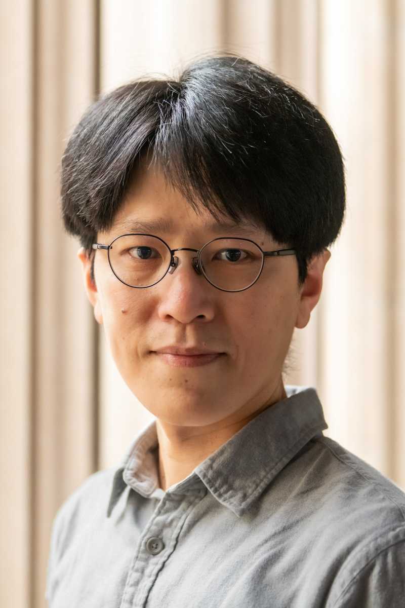 A portrait of Yu-chi Chang, a person with short black hair, glasses, and a gray shirt.