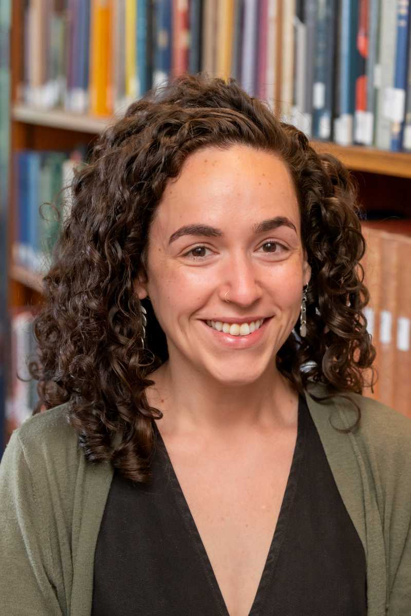 A portrait of Rebecca Peretz-Lange, a person with long dark brown hair and an olive green shirt.