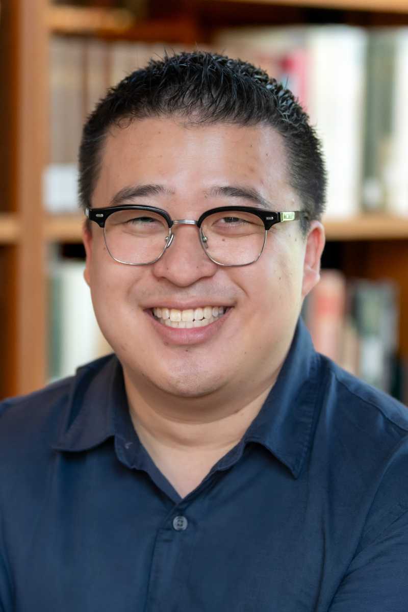 A portrait of Harrison Shieh, a person with short black hair, glasses, and a dark blue shirt.