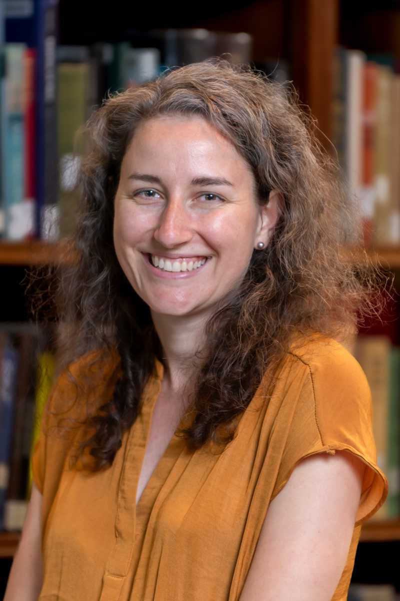 A portrait of Taylor Teitsworth, a person with long brown hair and an orange shirt.