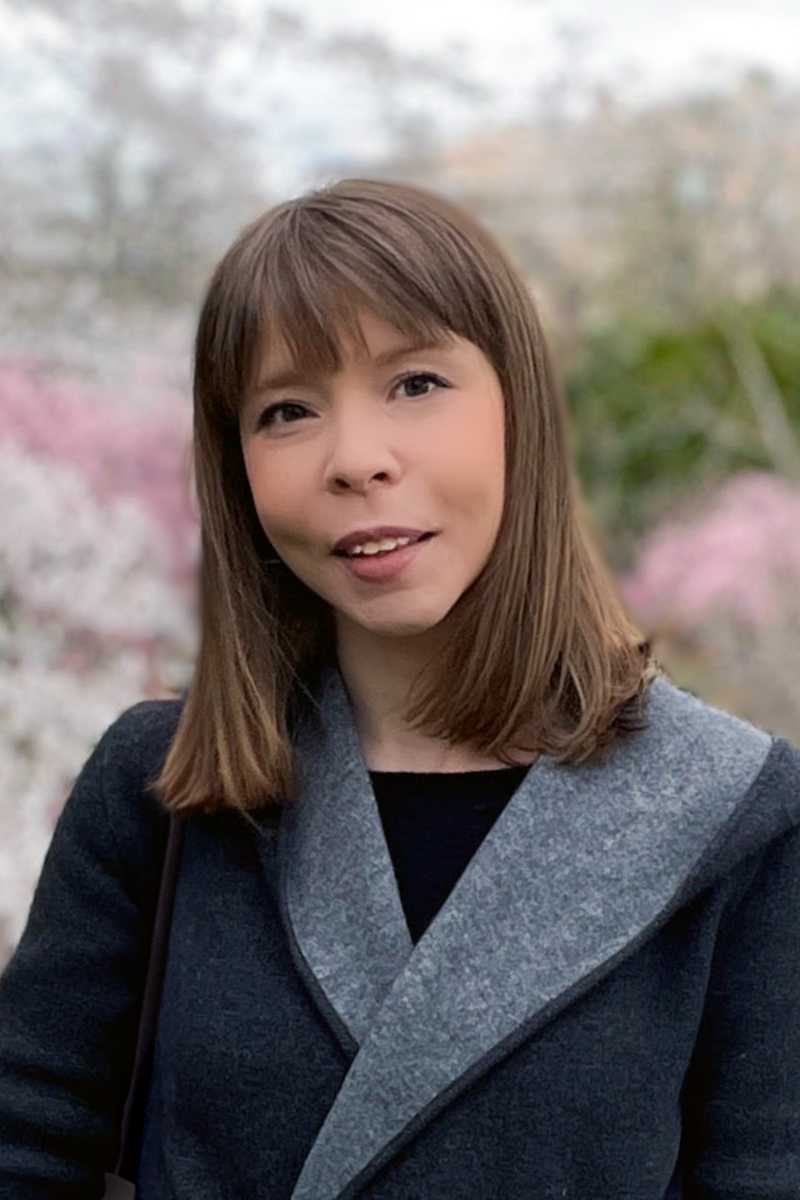 A portrait of Petya Andreeva, a person with long brown hair and a dark coat.