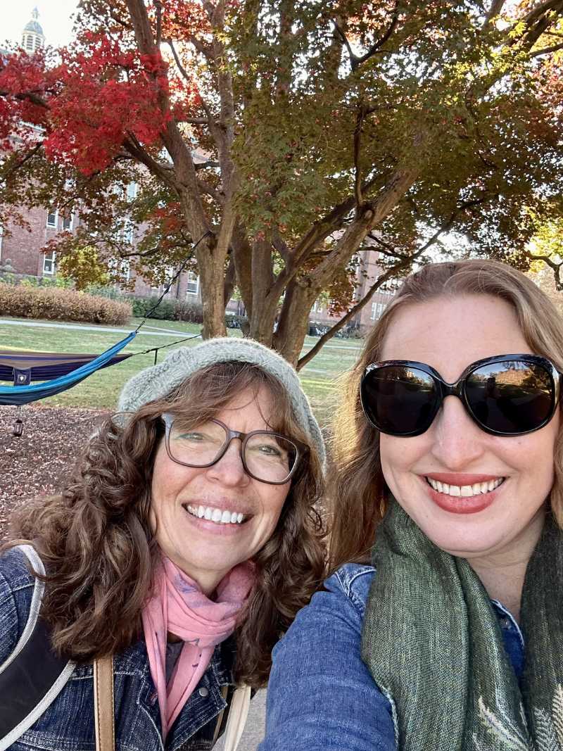 Dr. Michelle Monje ’98, a person with long blond hair and sunglasses, takes a selfie with Kate Susan, a person with long brown hair and glasses.