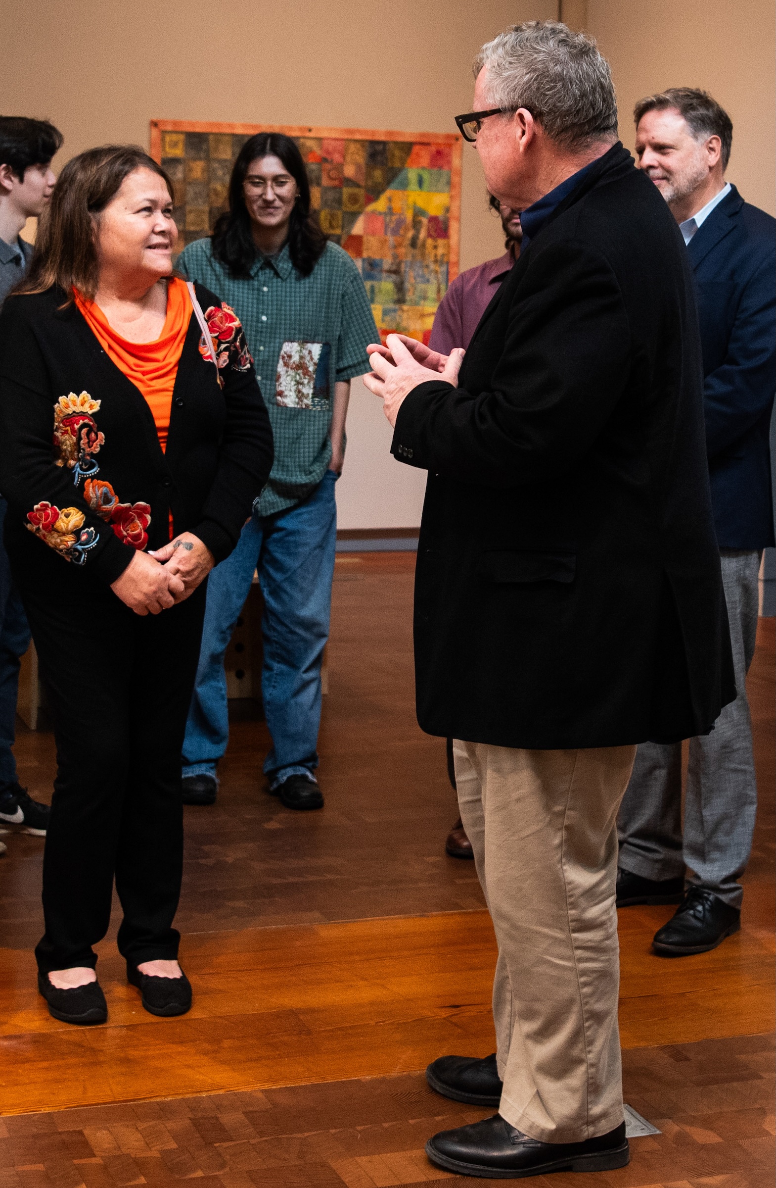 People standing in an art gallery smiling and talking.