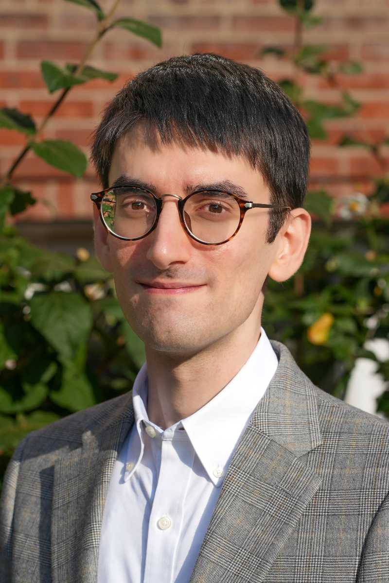 A photo of Pier Carlo Tommasi, a person with short black hair, glasses, and a gray suit jacket.