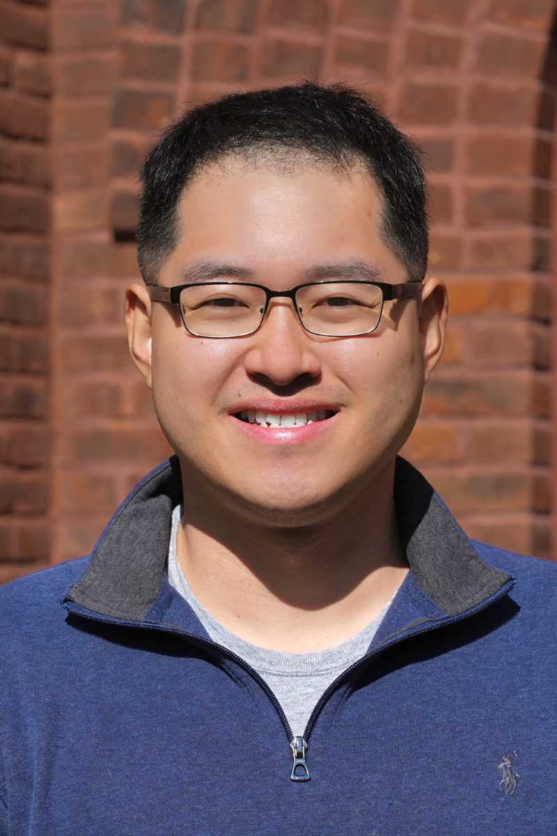 A portrait of Zhengren Zhu, a person with short black hair, glasses, and a blue shirt.