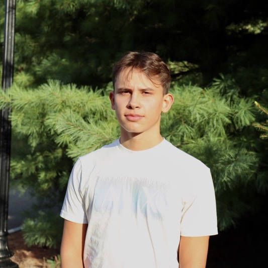 A portrait of Andi Buqa, a person with short brown hair and a white T-shirt.